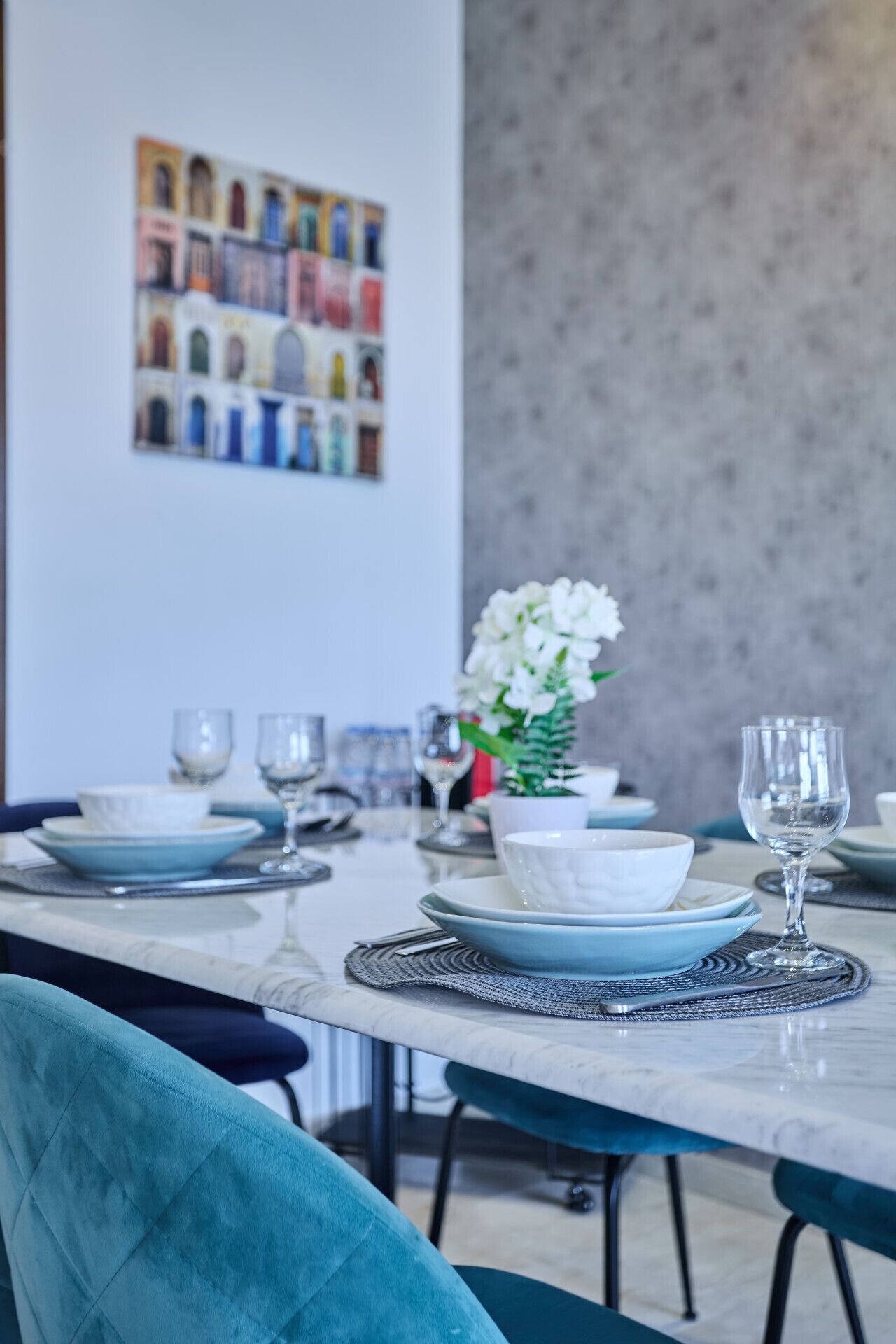 Una mesa de comedor con platos, vasos y un jarrón de flores.