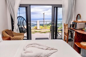 Habitación de hotel con cama, una silla, una mesita y vistas al exterior.