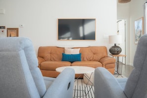 A living room with a brown sofa, a round coffee table, and a lamp on a side table.
