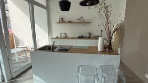 A modern kitchen with a central island, pendant lights, and a view of the outside.