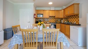 A compact kitchen with wooden cabinets, a microwave, and a dishwasher. - Spacious Townhouse by Shortstays (Gaillimh)