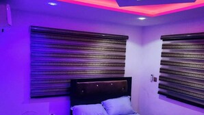 Ein Schlafzimmer mit einem Bett, einem Ventilator und gemusterten Vorhängen.
