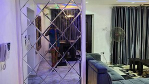 Ein Zimmer mit Glastrennwand, einer Couch, einem Ventilator und einem gemusterten Teppich.