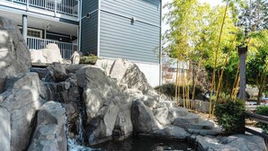 Een rotstuin met een kleine waterval, omringd door grote rotsen en een vijver.