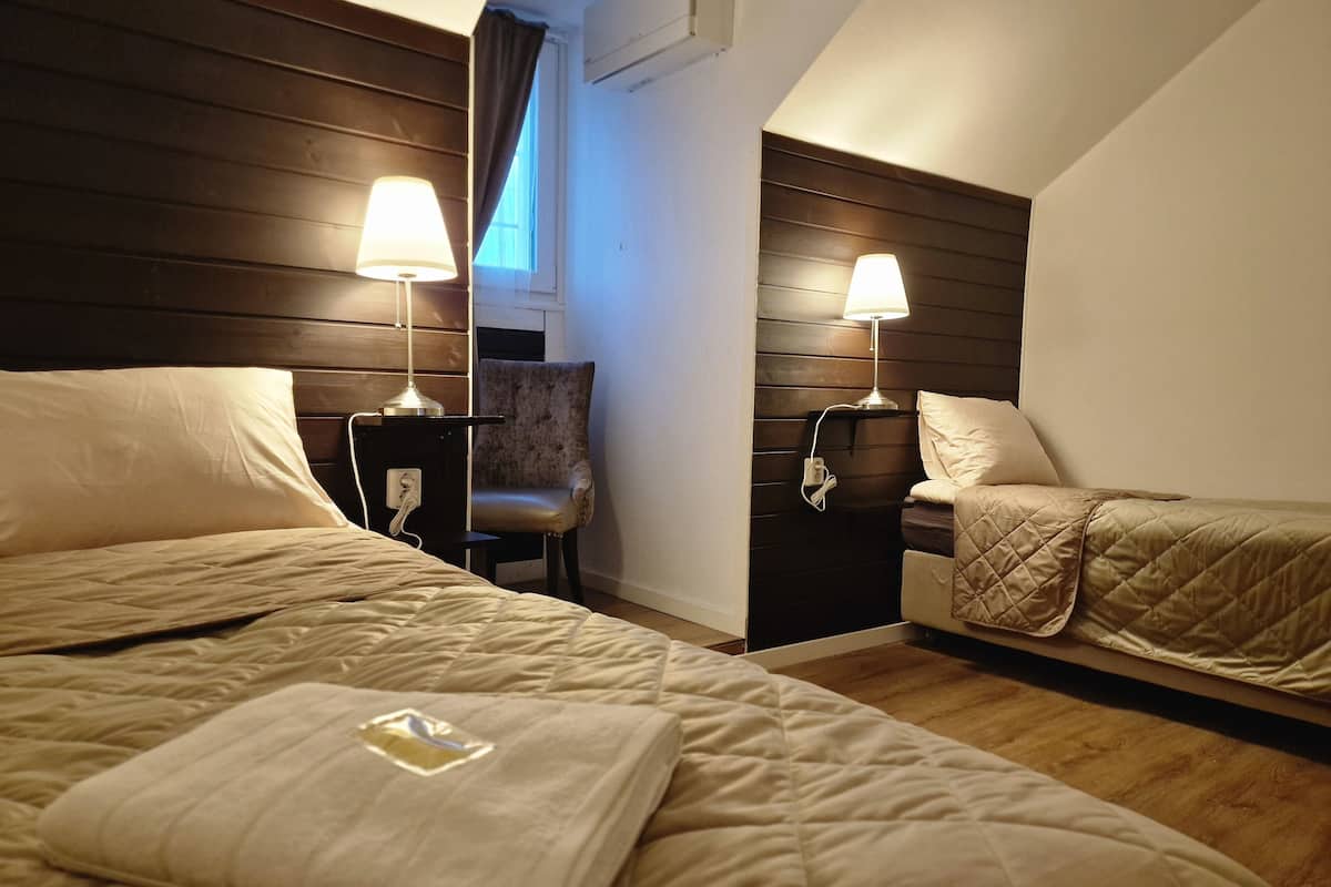 A hotel room with two beds, a chair, and two bedside lamps.