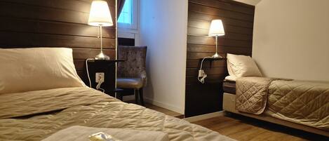 A hotel room with two beds, a chair, and two bedside lamps.