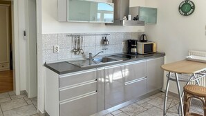 A modern kitchen with stainless steel appliances, a built-in microwave, and a wall-mounted clock. - 1 bedroom nice apartment in Barbat (Barbat)