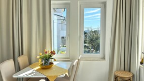 A dining area with a table, chairs, a vase of flowers, and a view through a window. - 1 bedroom nice apartment in Barbat (Barbat)