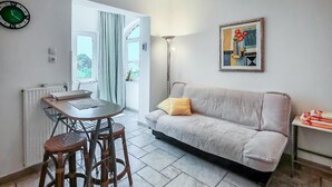 A living room with a sofa, a table with chairs, a lamp, and a painting on the wall. - 1 bedroom nice apartment in Barbat (Barbat)