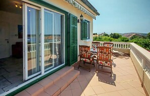 Een balkon met een tafel en stoelen, een schuifpui en uitzicht op het landschap.