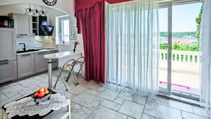 Eine moderne Küche mit Essbereich, einem Tisch mit Obstschale und Blick auf Grünfläche durch das Fenster.