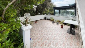A rooftop patio with potted plants, a glass balustrade, and a white table. - Gorgeous apartment in Rab with house sea view (Rab)