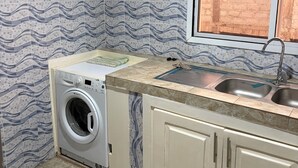 Una cocina con lavadora, ventana con vistas y azulejos de pared con diseño.