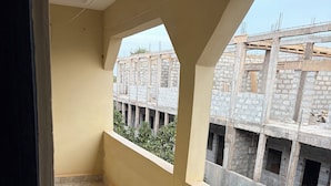 Un balcón con suelo de baldosas, vista a una obra en construcción y una pared lisa.