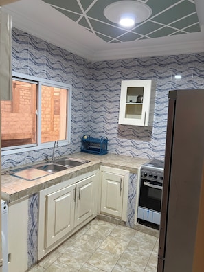 Una cocina con pileta, alacenas, ventana y estufa.