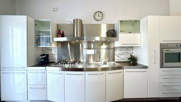Una cucina moderna con cappa in acciaio inossidabile, forno integrato e un orologio a parete.