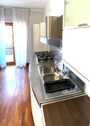 A kitchen with a stainless steel stove, a sink, and a window with curtains. - Entire Apartment for 5 with parking near Syracuse Greek Theater (Siracusa)