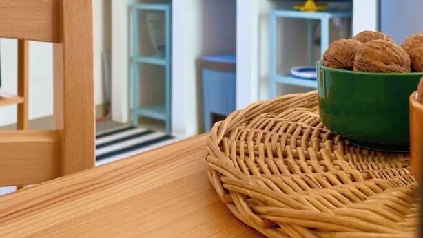 A dining area with a wooden table, a woven placemat, and a green bowl with walnuts. - 100mt from the sea of San Foca di Melendugno (San Foca)