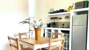 A dining area with a wooden table and chairs, a potted plant, and a kitchen with a refrigerator and shelves. - 100mt from the sea of San Foca di Melendugno (San Foca)