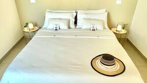 A bed with a white bedspread, two white pillows, a round woven rug with tassels, and two bedside tables with lamps. - 100mt from the sea of San Foca di Melendugno (San Foca)