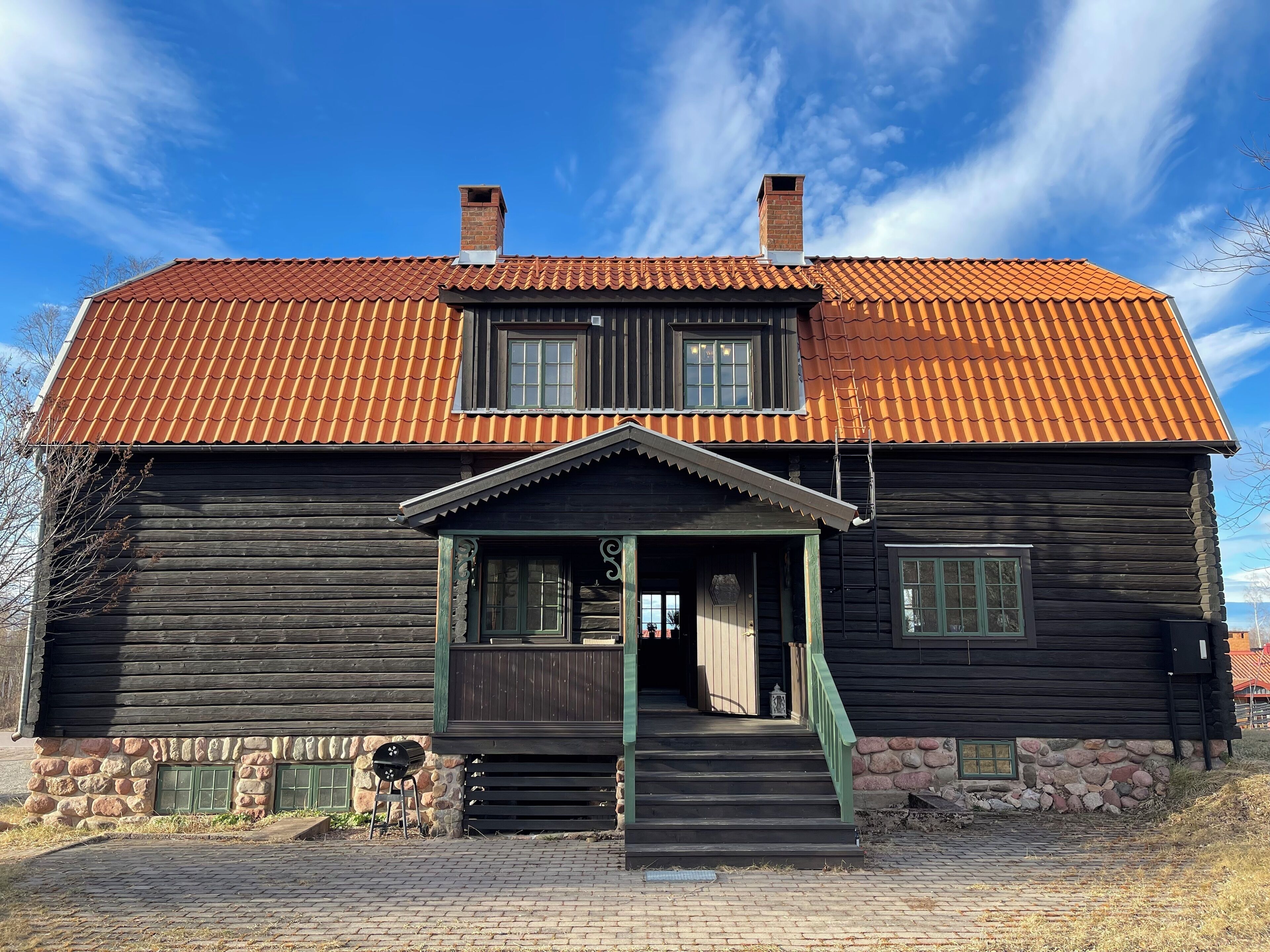 A log cabin with a porch, two chimneys, and a stone foundation.