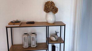Een houten console tafel met een vaas gedroogde bloemen, twee lantaarns en een keramieken spaarvarken.