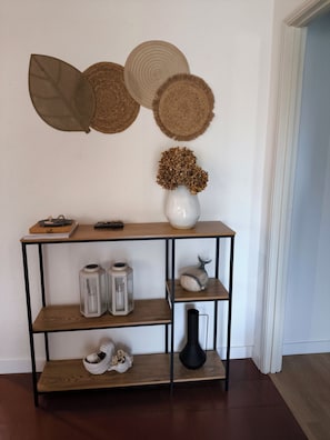 A wooden console table with a vase of dried flowers, two lanterns, and a ceramic piggy bank.