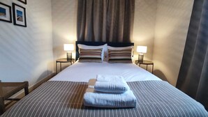 Een hotelkamer met een groot bed, twee bedlampen, een stoel en uitzicht op zee.