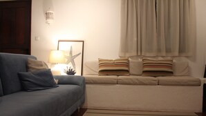 Een woonkamer met een bank, een gestreept vloerkleed en een zeester decoratie.