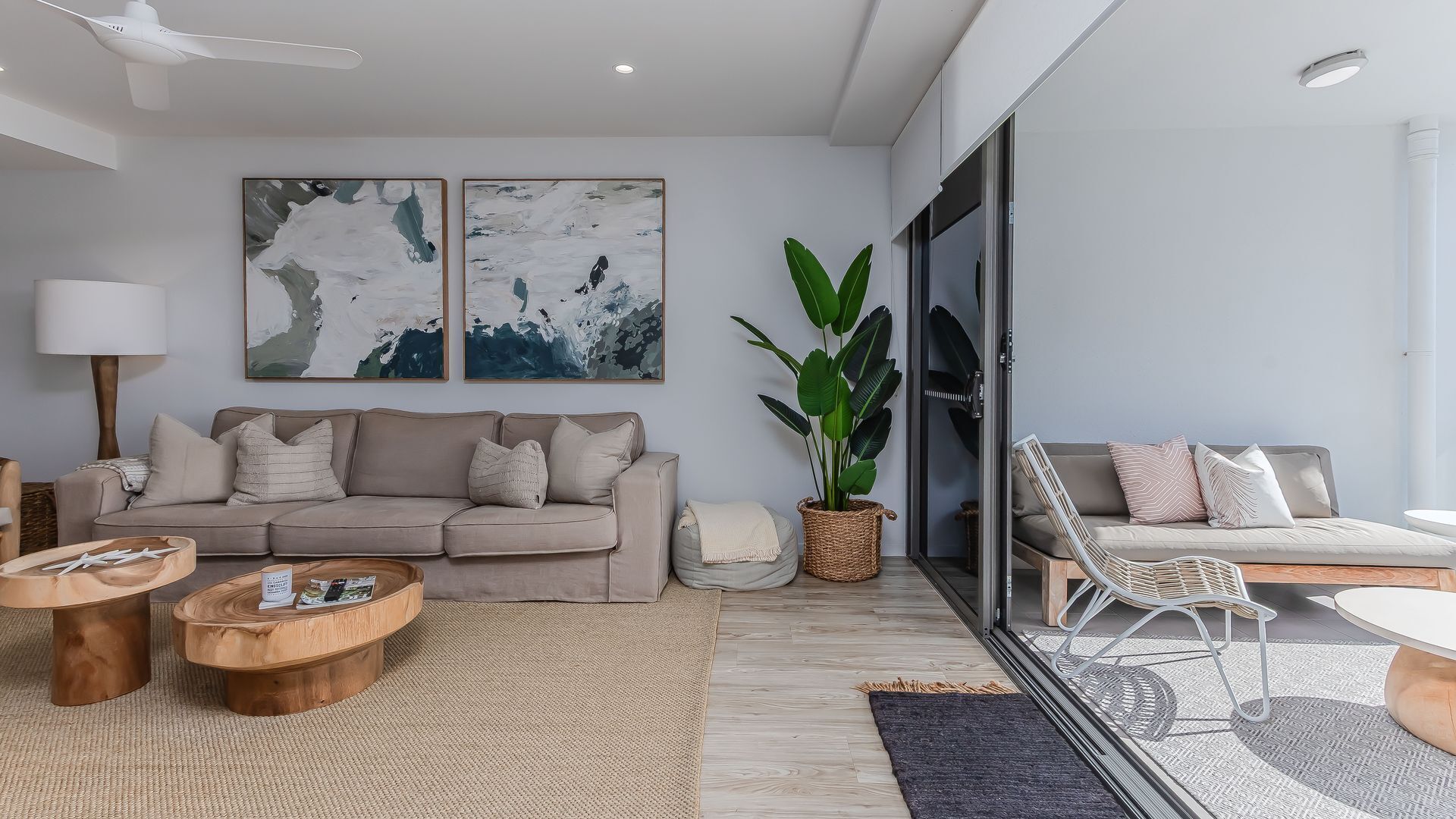 Een moderne woonkamer met een bank, salontafel en een grote plant.