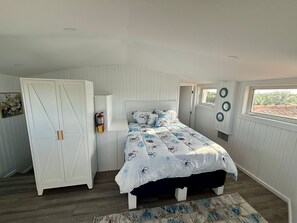 A bedroom with a bed, wardrobe, and a window. - Dockside Getaway Spacious 4 Bedroom Waterfront Retreat Stylish and Comfortable (North Sound Estates)