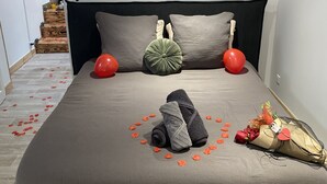 Une chambre à coucher bien rangée, avec un lit, des oreillers, une petite étagère et un luminaire fixé au mur.