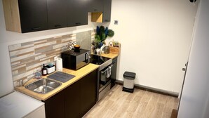 Une cuisine de taille réduite, équipée d’un évier, d’une cuisinière et de meubles de rangement noirs.