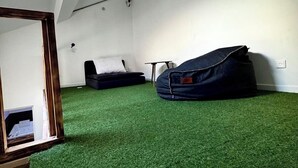 Une pièce avec un plafond en pente, un fauteuil en forme de poire, une petite table et une fenêtre.