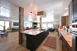 Eine geräumige Küche mit einer großen Kochinsel, Holzbalken an der Decke und einem Essbereich mit Tisch und Stühlen.