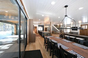 Eine moderne Küche mit einem langen Holztisch, einer Bar und einer Treppe, die in ein Obergeschoss führt.