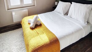 Ein Schlafzimmer mit einem Bett, einem Fenster und zwei Wandbildern.