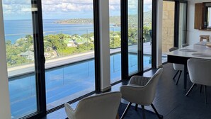 A modern room with large windows, a dining area, and a view of the sea.