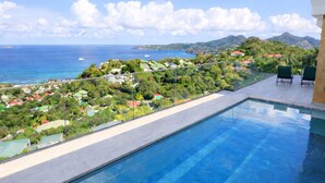 A swimming pool with a view of a coastal town and mountains.