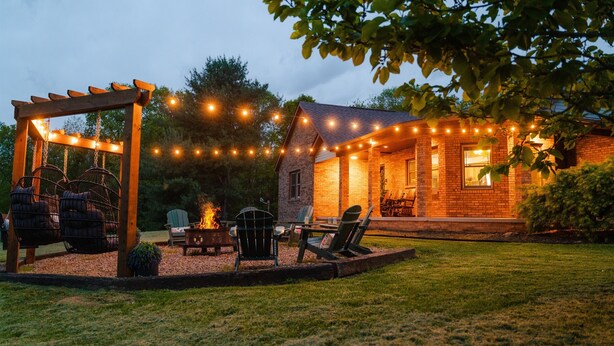 A patio with outdoor seating, a fire pit, and string lights. - Rolling Ridge | Sleeps 23, GameRoom, Pets, Sauna, HeatedPool, Theater, & More (Laurelville)