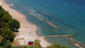A coastal beach with clear water, a sandy shore, and a pier extending into the sea. - AK Village Rooms - Peloponnese Comfy Gem (Nafplio)