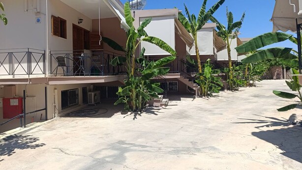 A residential area with multiple houses, a balcony, and a concrete courtyard with banana plants. - AK Village Rooms - Peloponnese Comfy Gem (Nafplio)