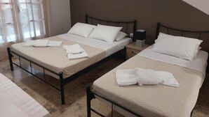 Two single beds with white linens and pillows, a bedside table with a lamp, and a window with sheer curtains. - AK Village Rooms - Peloponnese Comfy Gem (Nafplio)