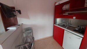 A compact kitchen with a sink, a dishwasher, and a small dining area with a chair. - Corfu Frodo Studios, Steps Away From the Beach (Corfu)