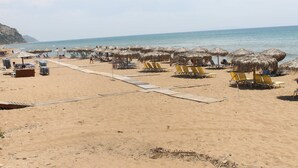 A beach with sun loungers and thatched umbrellas, a sandy path, and a view of the sea. - Corfu Frodo Studios, Steps Away From the Beach (Corfu)