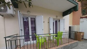 A balcony with a metal railing, two green chairs, and a trash bin. - Corfu Frodo Studios, Steps Away From the Beach (Corfu)
