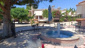 Une terrasse extérieure avec une piscine, des sièges et un arbre.