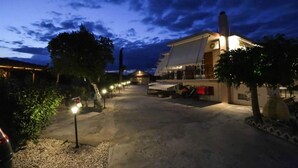 Un hôtel doté d’une allée pavée, d’un éclairage extérieur et d’un bâtiment dont le toit est en pente.