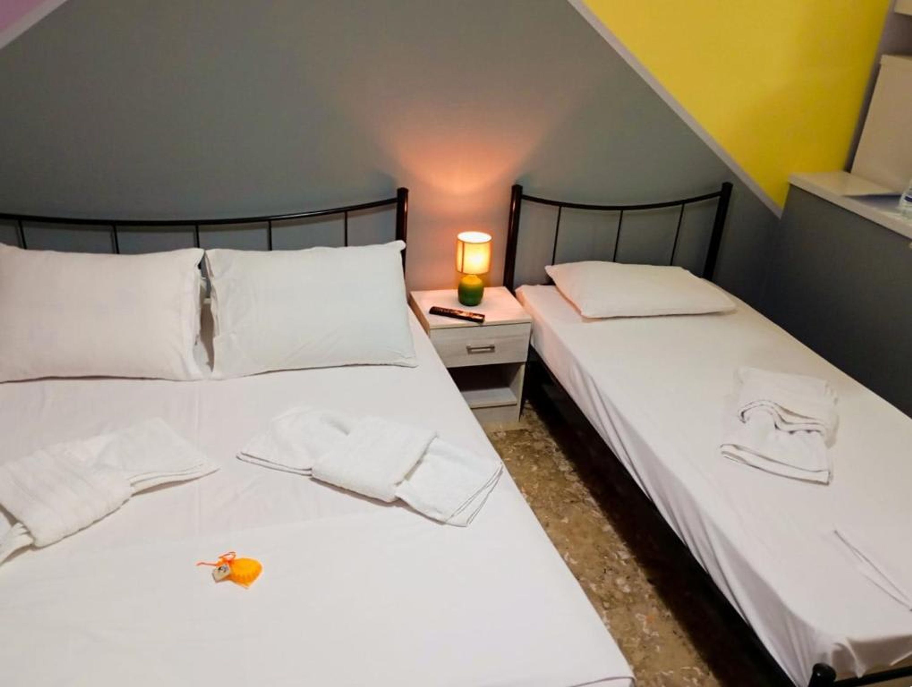 A twin room with two beds, a nightstand with a lamp, and a small table.