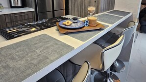 A modern kitchen with a central island, bar stools, and pendant lighting. - Villa De Gloria II - Elevated Signature Stay (Bayamon)
